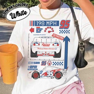 K&ouml;nnte beinhalten: Ein wei&szlig;es T-Shirt mit einem Grafikdruck eines Rennwagens und dem Text Lightning McQueen, Rust-eze, 198 MPH, 95, Octane Gain und RPM. Das Design zeigt eine R&uuml;ckansicht, eine Seitenansicht eines Rennwagens, einen Tacho und Karomuster.