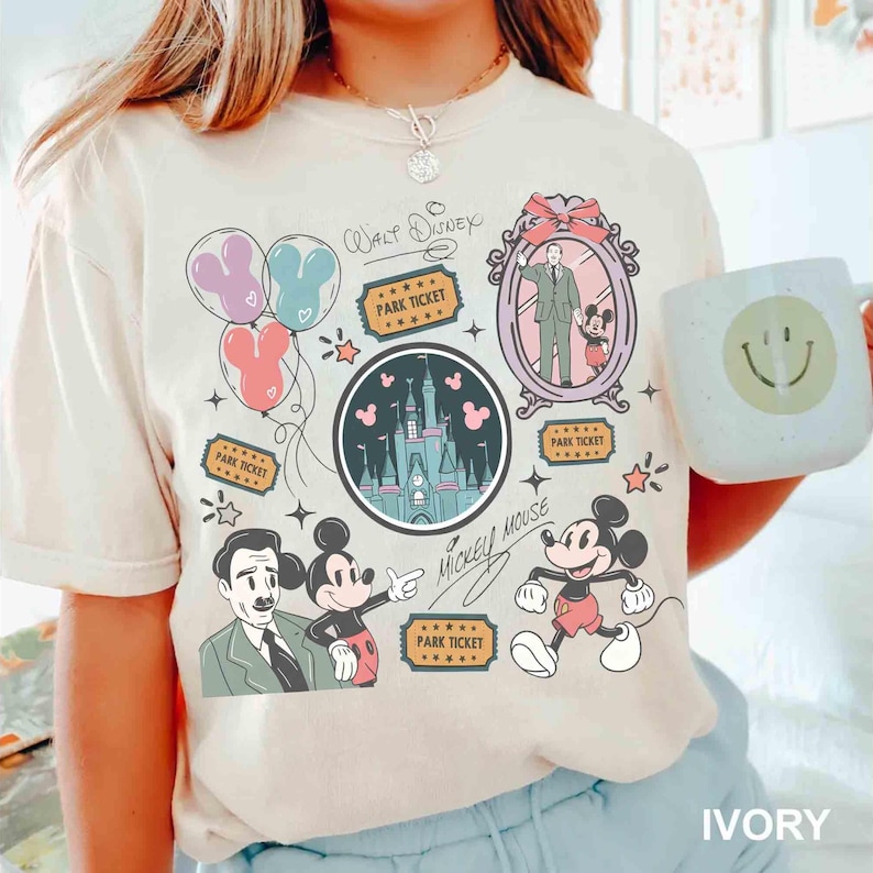 Peut inclure: T-shirt ivoire avec un motif sur le th&egrave;me de Disney. Le graphisme comprend Mickey Mouse, un ch&acirc;teau, des ballons et des billets de parc. Les mots "Walt Disney" et "Mickey Mouse" sont &eacute;galement pr&eacute;sents. Le t-shirt est &agrave; col rond et &agrave; manches courtes.