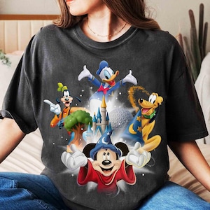 May include: Dark gray t-shirt featuring a colorful graphic of Disney characters Mickey Mouse, Donald Duck, Goofy, and Pluto, with a castle and a sphere in the background. The design has a vintage, distressed look.