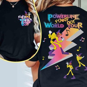 May include: Black t-shirt with a graphic of Goofy and his friends. The graphic says "Goofy" and is in a cartoon style. The t-shirt also has the text "Powerline Stand Out World Tour" in a colorful, stylized font.