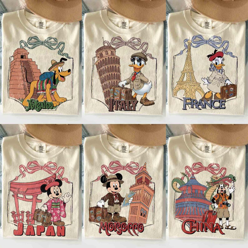 May include: Cream-colored t-shirts featuring travel-themed designs. Each shirt showcases a different country with a cartoon character and landmark: Mexico, Italy, France, Japan, Morocco, and China. The designs are framed with a decorative bow.