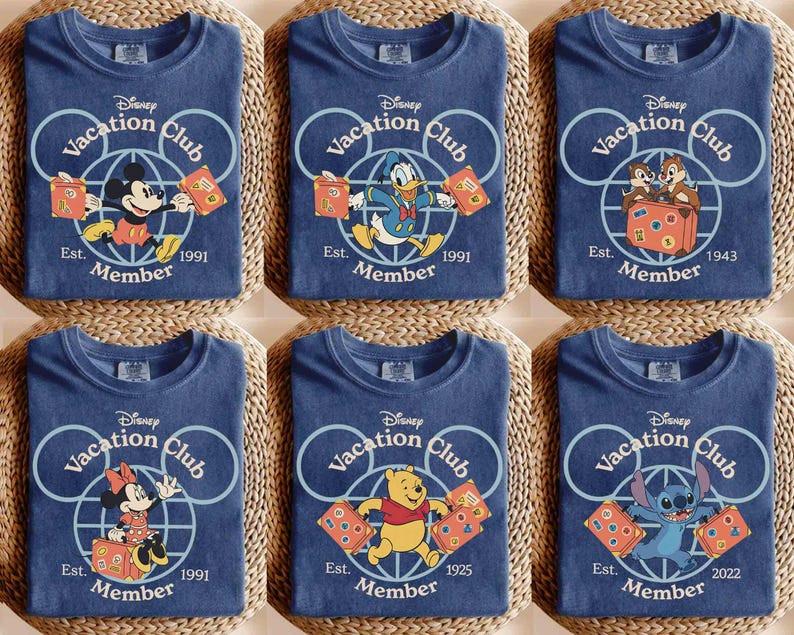 Puede incluir: Seis camisetas azules con personajes de Disney como Mickey Mouse, Donald Duck y Stitch. Cada camiseta tiene el logo "Disney Vacation Club" y el a&ntilde;o de fundaci&oacute;n. Las camisetas est&aacute;n dobladas sobre una superficie tejida.