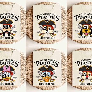 May include: Six white t-shirts with a cartoon pirate dog and duck design. The shirts feature the text "Yo Ho Yo Ho Pirates" and "Est. 2024 Life For Me".