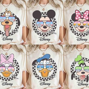 May include: Six different t-shirts featuring various Disney characters wearing sunglasses. Each character is surrounded by a checkered pattern and the word "Disney" is printed below. The characters include Mickey Mouse, Minnie Mouse, Donald Duck, Goofy, Pluto, and Daisy Duck.