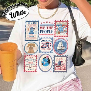 以下が含まれることがあります： 愛国的な切手風のデザインが施された白いTシャツ。Tシャツには、7月4日、アメリカ国旗、「We the People」というフレーズに関連するテキストとイラストが描かれています。また、Tシャツには「America 250 1776-2026」という文字も入っています。