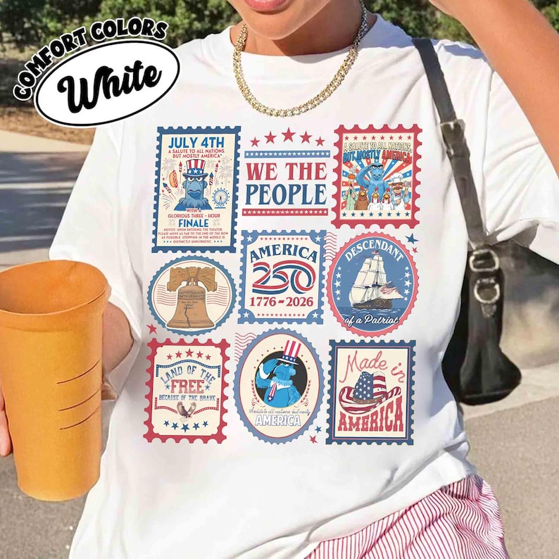 以下が含まれることがあります： 愛国的な切手風のデザインが施された白いTシャツ。Tシャツには、7月4日、アメリカ国旗、「We the People」というフレーズに関連するテキストとイラストが描かれています。また、Tシャツには「America 250 1776-2026」という文字も入っています。