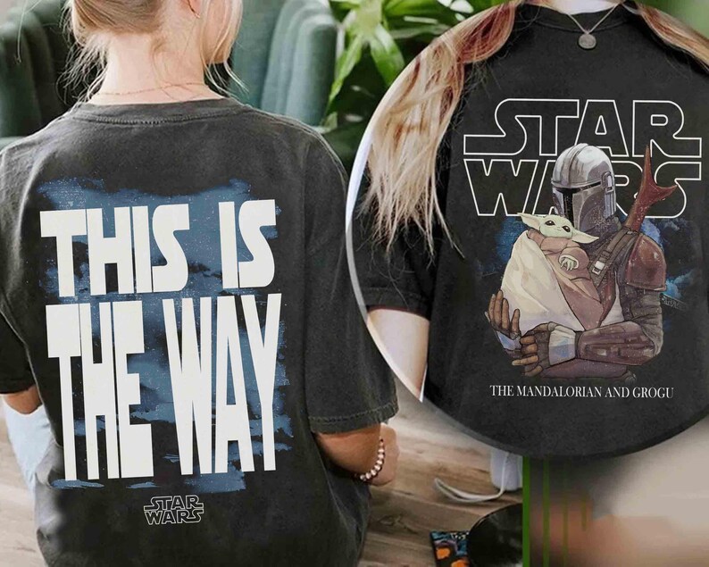 May include: A black t-shirt featuring a graphic of The Mandalorian and Grogu with the text Star Wars above them. The back of the shirt displays the text This Is The Way in large white letters over a blue background with the Star Wars logo below.