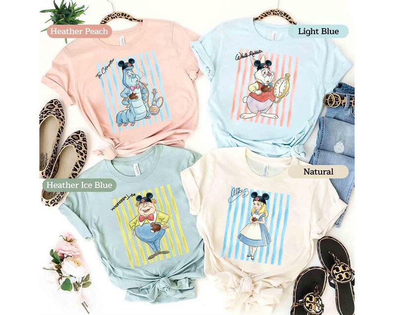 May include: Four short-sleeve t-shirts in heather peach, light blue, heather ice blue, and natural colors. Each shirt features a graphic of a character wearing Mickey Mouse ears, including The Caterpillar, White Rabbit, Tweedledee, and Alice.