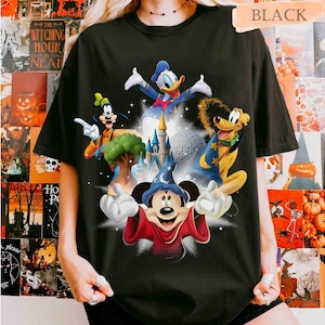 May include: Black t-shirt featuring a colorful graphic of Disney characters including Mickey Mouse, Donald Duck, Goofy, and Pluto. The design includes a castle and a sphere, with the word "BLACK" at the top.