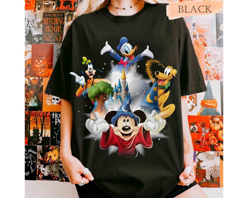 May include: Black t-shirt featuring a colorful graphic of Disney characters including Mickey Mouse, Donald Duck, Goofy, and Pluto. The design includes a castle and a sphere, with the word "BLACK" at the top.