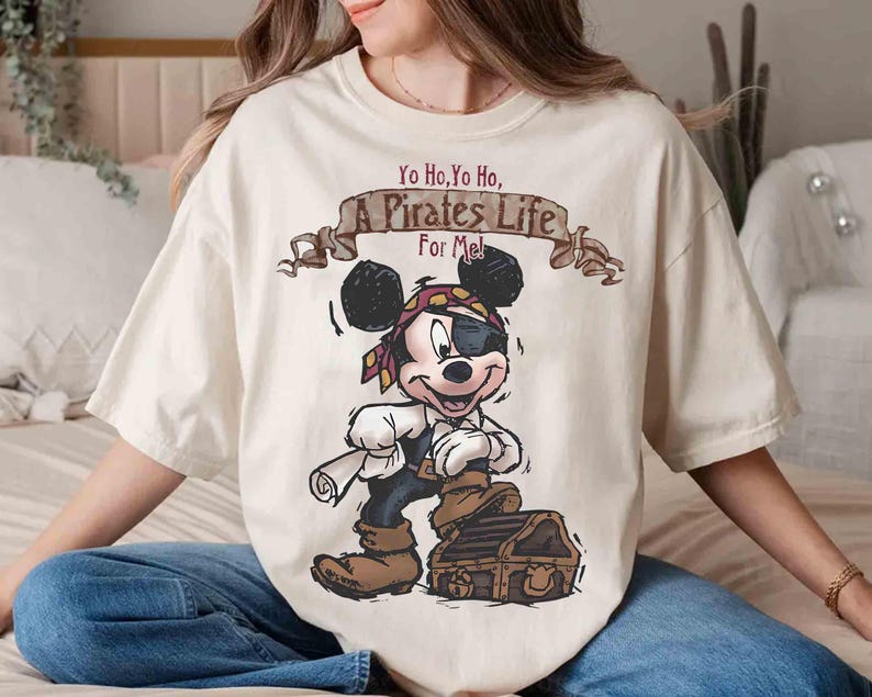 Puede incluir: Una camiseta blanca con una imagen de dibujos animados de Mickey Mouse vestido de pirata. El texto "Yo Ho, Yo Ho, A Pirates Life For Me!" est&aacute; impreso sobre Mickey Mouse.