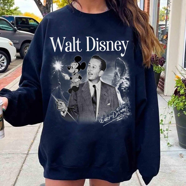 Puede incluir: Una sudadera de cuello redondo en azul marino oscuro con un estampado gr&aacute;fico de Walt Disney en traje y corbata, con Mickey Mouse sobre su hombro. El texto Walt Disney est&aacute; impreso en blanco sobre la imagen, con una firma en la parte inferior.