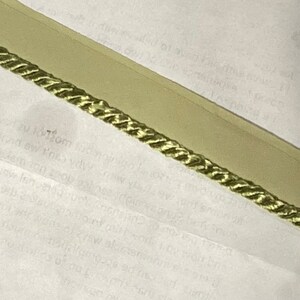 May include: A close-up of a light green rope trim with a braided design. The trim is on a white background.