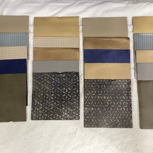 May include: A collection of fabric swatches in various colors and textures, including beige, brown, gray, blue, and green. The swatches are arranged in rows and columns, and some have a geometric pattern.