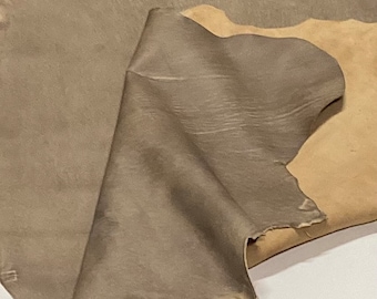 May include: A piece of brown leather with a lighter brown patch. The leather is folded and has a textured surface.