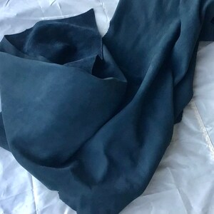 May include: A piece of dark blue suede fabric folded on a white surface.