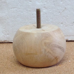 May include: A round wooden furniture leg with a threaded metal screw in the top. The leg is light brown and has a natural wood grain.