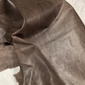 May include: A piece of brown leather with a textured surface.