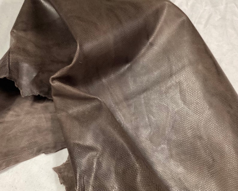 May include: A piece of brown leather with a textured surface.