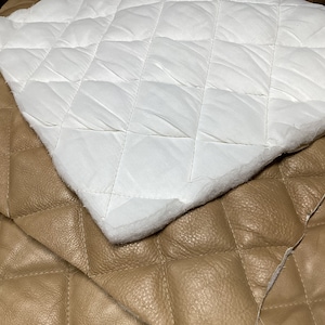 May include: Two pieces of quilted fabric, one white and one brown. The white fabric is on top of the brown fabric. Both fabrics have a diamond pattern.