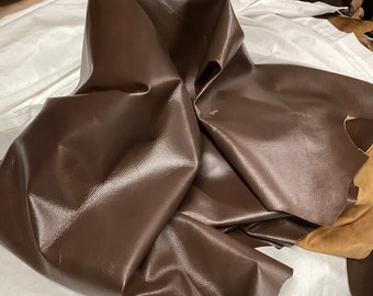 May include: A piece of brown leather, folded and creased, showing its texture and color.