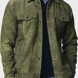 Puede incluir: Chaqueta de ante verde oliva con dos bolsillos en el pecho y cierre de botones. La chaqueta tiene un cuello clásico y mangas largas. Se lleva una camisa azul debajo. Prenda de vestir exterior elegante.