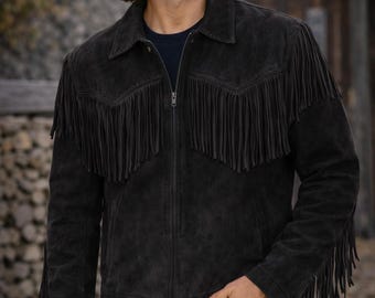 May include: Black suede jacket with fringe detailing across the chest and sleeves. The jacket has a zip-up front and a classic collar. The model is wearing blue jeans. This western-style jacket is a great addition to any wardrobe.
