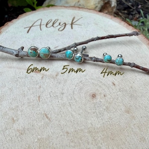 May include: Three pairs of turquoise stud earrings in 6mm, 5mm, and 4mm sizes, displayed on a wooden surface with a branch. The earrings have a silver bezel setting and a natural turquoise stone. The name "Ally K" is written in cursive.