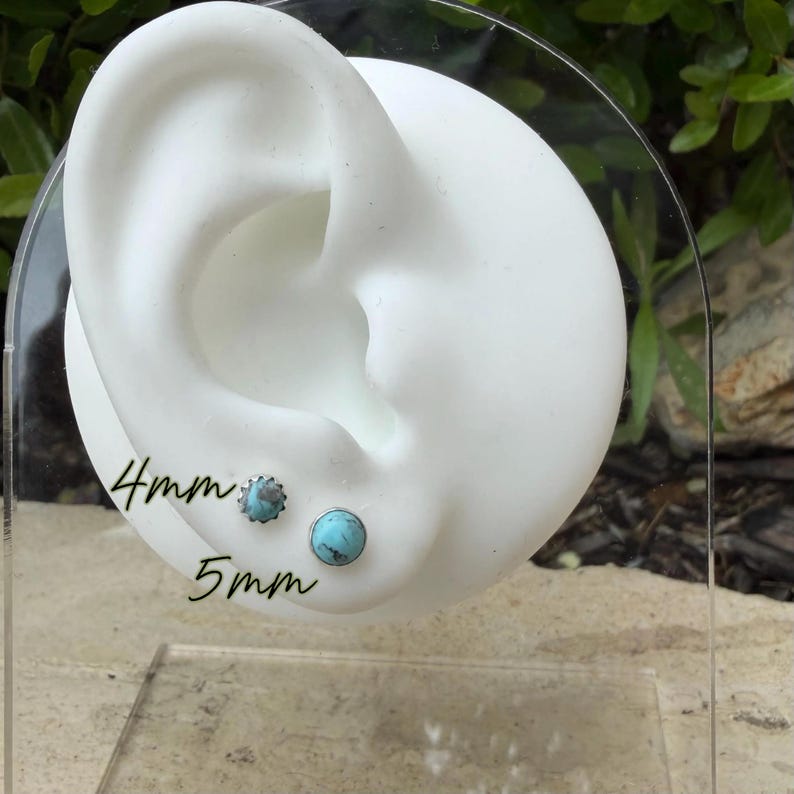 May include: Two pairs of turquoise stud earrings, one 4mm and the other 5mm, displayed on a white ear model. The earrings have a silver setting. The text "4mm" and "5mm" is written on the display.