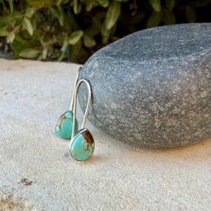 Pu&ograve; includere: Un paio di orecchini a goccia con turchese caratterizzati da venature naturali color marrone, montati su ganci in metallo color argento. Le pietre presentano una vivace tonalit&agrave; blu-verde con distinti motivi organici, sospese a semplici ganci curvi.
