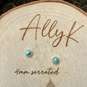 May include: Two small turquoise stud earrings with a serrated edge, each 4mm in diameter, are displayed on a wooden surface. The word "Allyk" is written in a cursive font above the earrings, and the text "4mm serrated" is below.