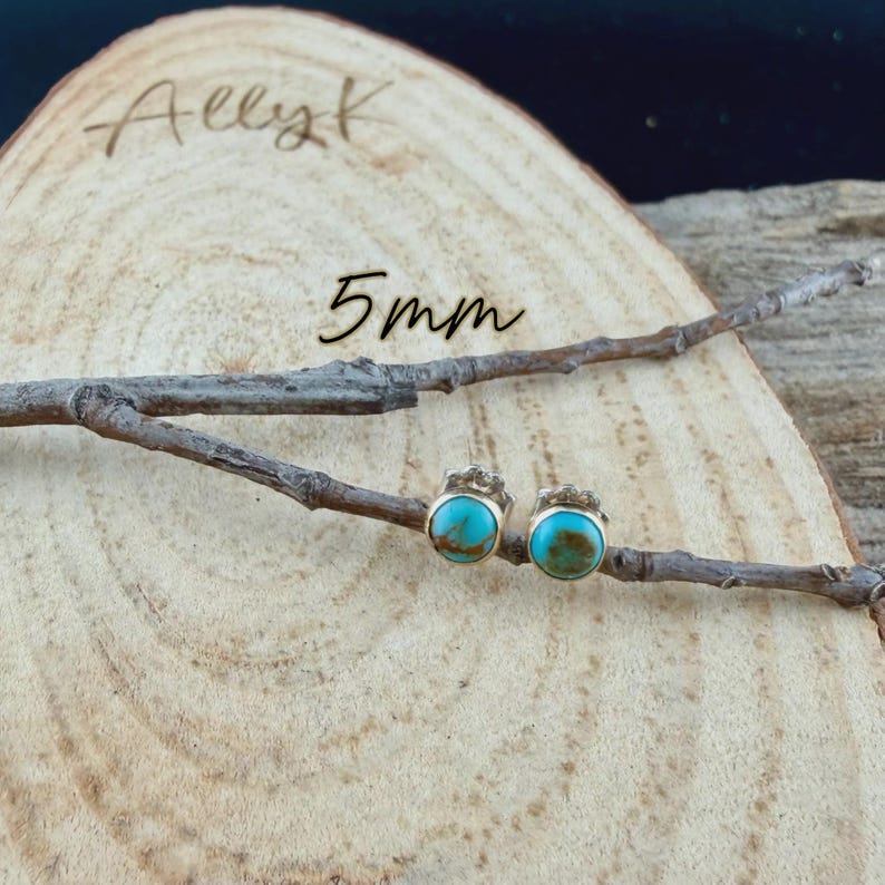 K&ouml;nnte beinhalten: Ein Paar t&uuml;rkisfarbene Ohrstecker mit goldfarbenen Fassungen, pr&auml;sentiert auf einer Holzoberfl&auml;che mit einem Ast. Die Ohrringe sind 5 mm gro&szlig;. Der Name "Allyk" ist in Kursivschrift auf dem Holz geschrieben.
