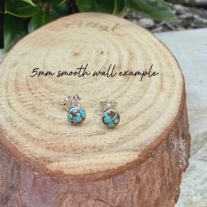 May include: A pair of silver stud earrings with turquoise and brown stone inlays. The earrings are displayed on a wooden surface. The text "5mm smooth wall example" is written on the wood.