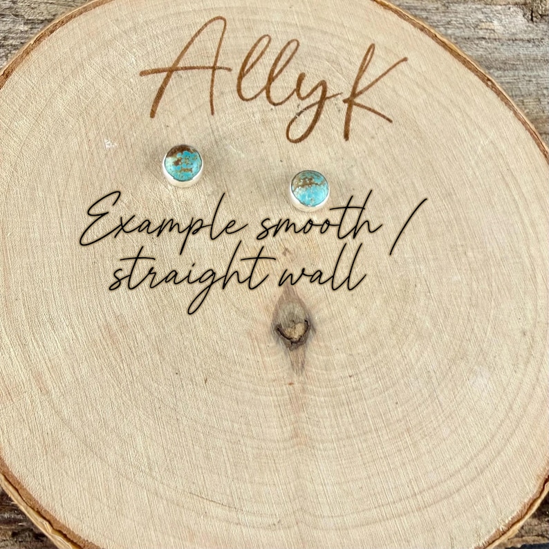 May include: Two small turquoise and silver stud earrings on a wooden surface. The earrings have a round turquoise stone set in a silver bezel. The wooden surface has the name "Allyk" and the text "Example smooth / straight wall" written on it.