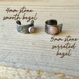 May include: Two silver-toned rings with textured bands and round pink stones. The left ring features a 4mm stone in a smooth bezel, while the right ring features a 5mm stone in a serrated bezel. Text reads 4mm stone smooth bezel and 5mm stone serrated bezel.