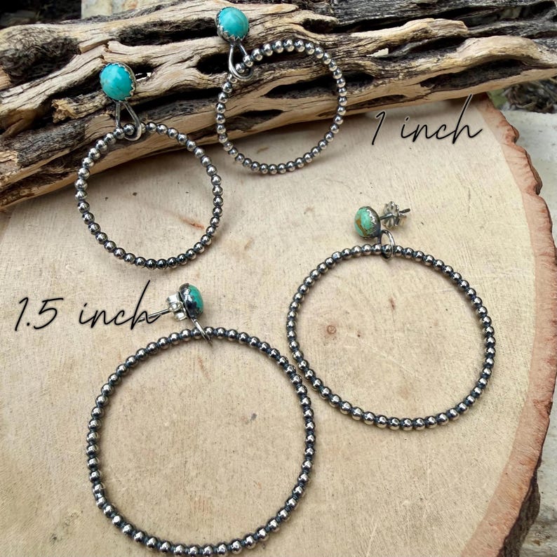 Puede incluir: Pendientes de aro plateados con detalles turquesa. Los pendientes est&aacute;n disponibles en dos tama&ntilde;os: 2,5 cm y 3,8 cm. Los aros est&aacute;n hechos de peque&ntilde;as cuentas redondas. Los pendientes se muestran sobre una superficie de madera.