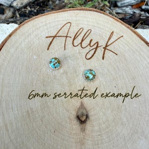 May include: Two small, round earrings with turquoise and brown stones are displayed on a wooden surface. The earrings are labeled as a "6mm serrated example" and the name "Allyk" is written above them.