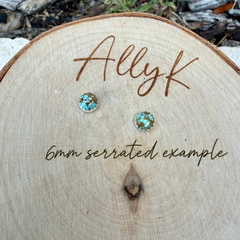 May include: Two small, round earrings with turquoise and brown stones are displayed on a wooden surface. The earrings are labeled as a "6mm serrated example" and the name "Allyk" is written above them.