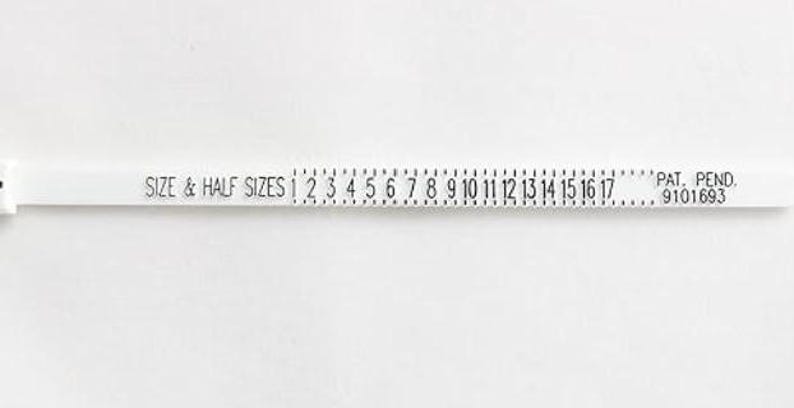 May include: White plastic ruler with black markings for measuring shoe sizes. The ruler shows sizes 1 through 17, with half sizes marked in between. The text "SIZE & HALF SIZES" is printed on the ruler, along with "PAT. PEND. 9101693".
