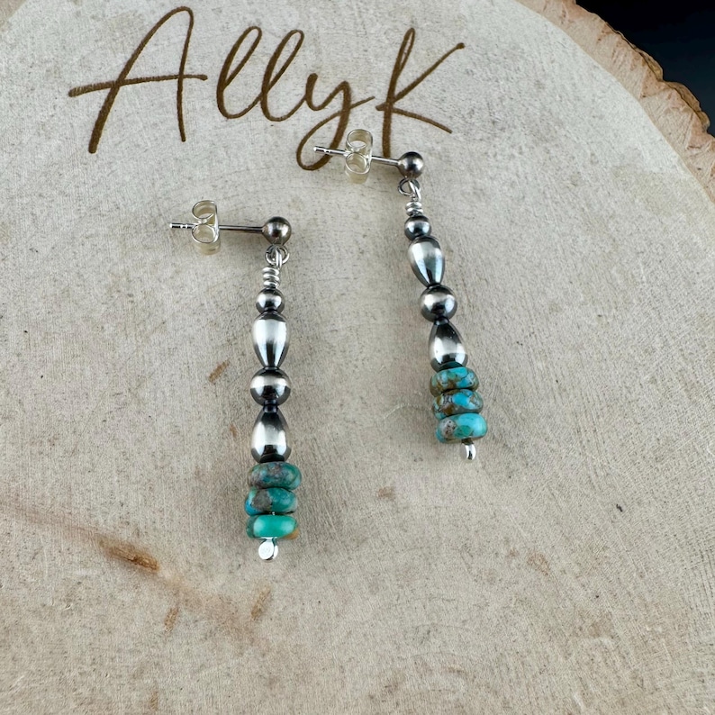 May include: A pair of silver dangle earrings with turquoise and silver beads. The earrings have a post backing and the text "Allyk" is written in cursive in the background.