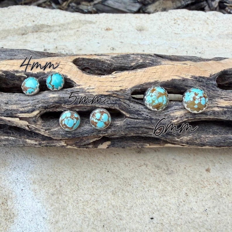 May include: Turquoise and brown stone stud earrings in 4mm, 5mm, and 6mm sizes. The earrings are set in silver-colored metal and displayed on a piece of driftwood. The text "4mm", "5mm", and "6mm" is written on the wood.