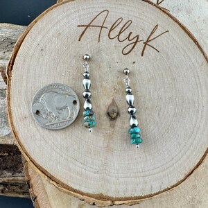 May include: A pair of dangle earrings with silver beads and turquoise chips. The earrings are displayed on a wooden surface with the handwritten text "Allyk". A US five-cent coin is next to the earrings.