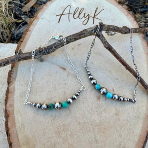 Peut inclure: Deux colliers en argent orn&eacute;s de perles turquoise et argent&eacute;es sont pr&eacute;sent&eacute;s sur une surface en bois. Les colliers ont un design de cha&icirc;ne d&eacute;licat et sont orn&eacute;s d'un m&eacute;lange de petites et de grandes perles d'argent, ainsi que de perles turquoise vibrantes. Le texte "Allyk" est visible.