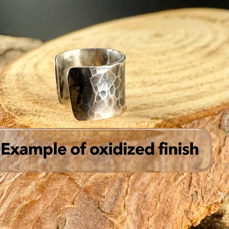 May include: A silver-colored ring with an oxidized finish. The ring has a hammered texture and an open design. The text "Example of oxidized finish" is visible in the image.