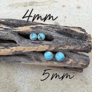May include: Two pairs of turquoise stud earrings, 4mm and 5mm, displayed on a piece of driftwood. The earrings have a silver setting and a bright blue stone with a mottled pattern. The text "4mm" and "5mm" is written in black.