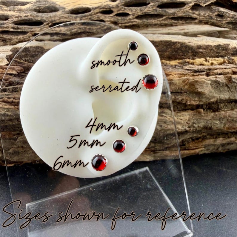 May include: A white ear-shaped display stand featuring six round red gemstone stud earrings. The text labels indicate smooth and serrated edge styles, with sizes 4mm, 5mm, and 6mm shown for reference on the display.