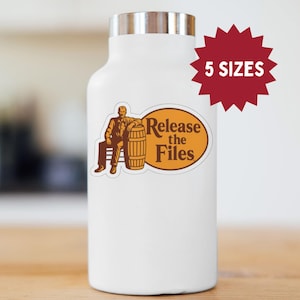Peut inclure: Gourde blanche avec un couvercle argenté. L'autocollant représente un homme assis à côté d'un tonneau, avec l'inscription "Release the Files". Une étoile rouge indique 5 tailles disponibles.