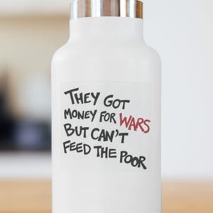 May include: White water bottle with a silver lid. The bottle has a sticker with the text "They Got Money For Wars But Can't Feed The Poor". The word "Wars" is in red.