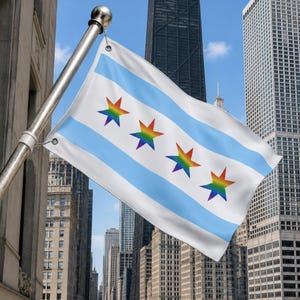 Puede incluir: Una bandera blanca con el diseño de la bandera de la ciudad de Chicago, con rayas azul claro y tres estrellas de colores arcoíris. La bandera está montada en un mástil plateado y ondea frente a un paisaje urbano con edificios altos.