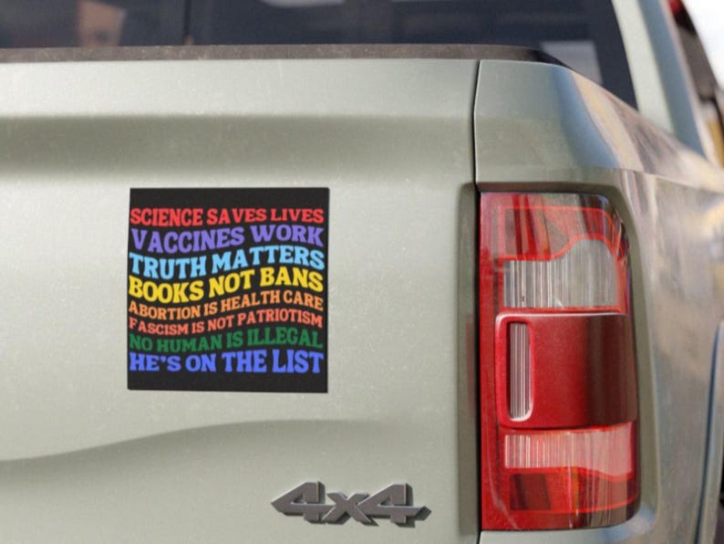 Pode incluir: Um autocolante retangular num ve&iacute;culo com o texto "SCIENCE SAVES LIVES, VACCINES WORK, TRUTH MATTERS, BOOKS NOT BANS, ABORTION IS HEALTH CARE, FASCISM IS NOT PATRIOTISM, NO HUMAN IS ILLEGAL, HE'S ON THE LIST" em cores do arco-&iacute;ris.